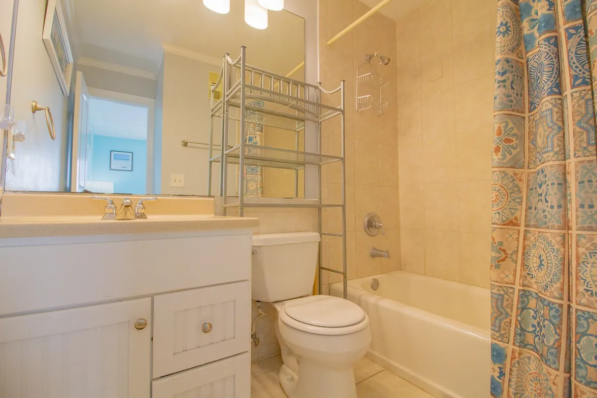A bright, clean bathroom with a bathtub, shower curtain, and a modern vanity. The setting is calm and inviting, perfect for refreshing showers or relaxing baths after a long day.