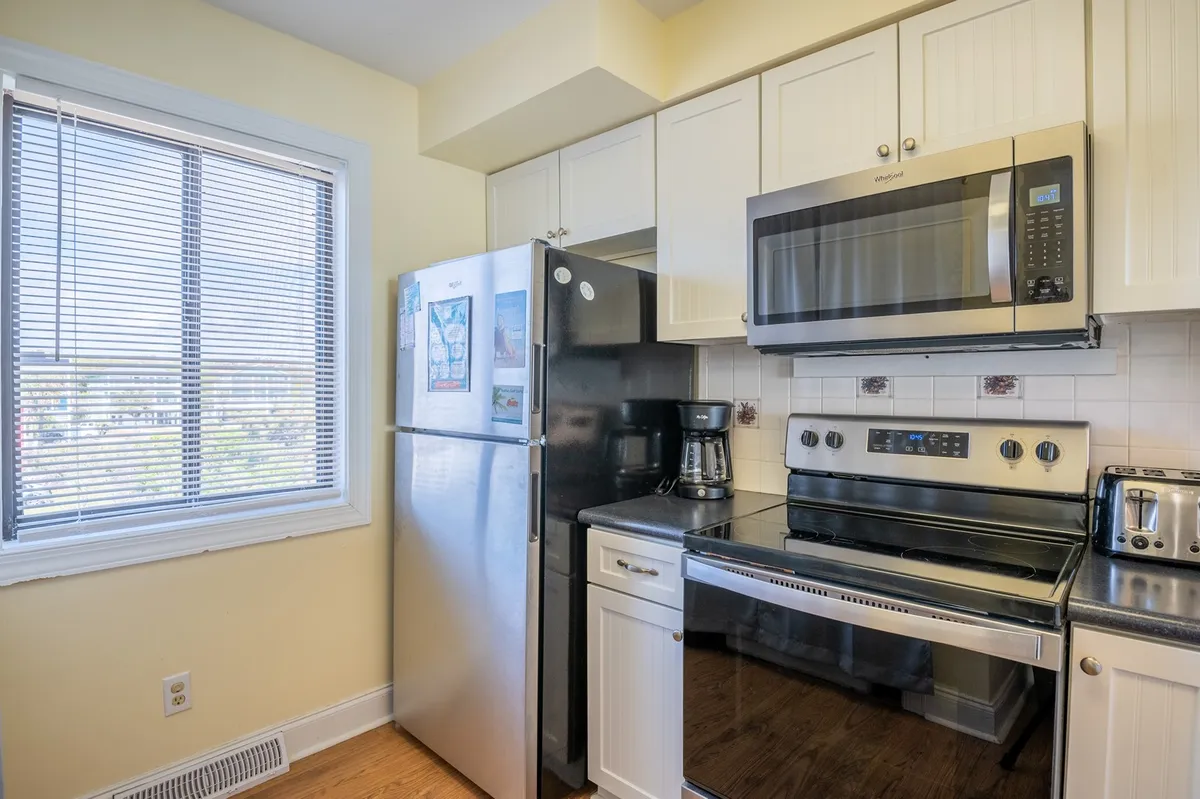 A kitchen scene featuring stainless steel appliances, a window letting in natural light, spacious countertops, and a coffee maker. The overall vibe is cozy yet highly functional, ideal for meal prep and casual dining. The scene suggests both solo and family cooking moments.