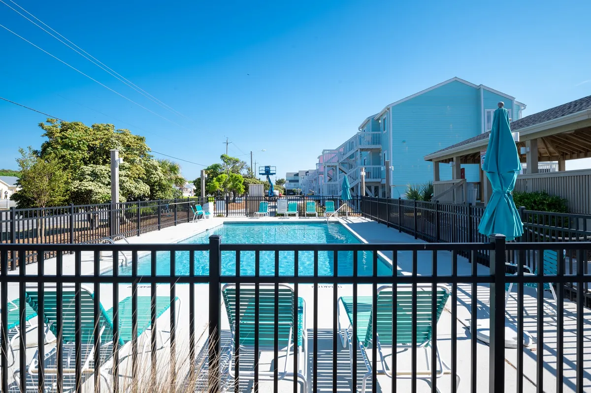 This exterior image shows a sparkling swimming pool surrounded by lounge chairs and umbrellas, with greenery and resort buildings in the background. The scene is lively and welcoming, perfect for families and groups to enjoy the outdoors together.